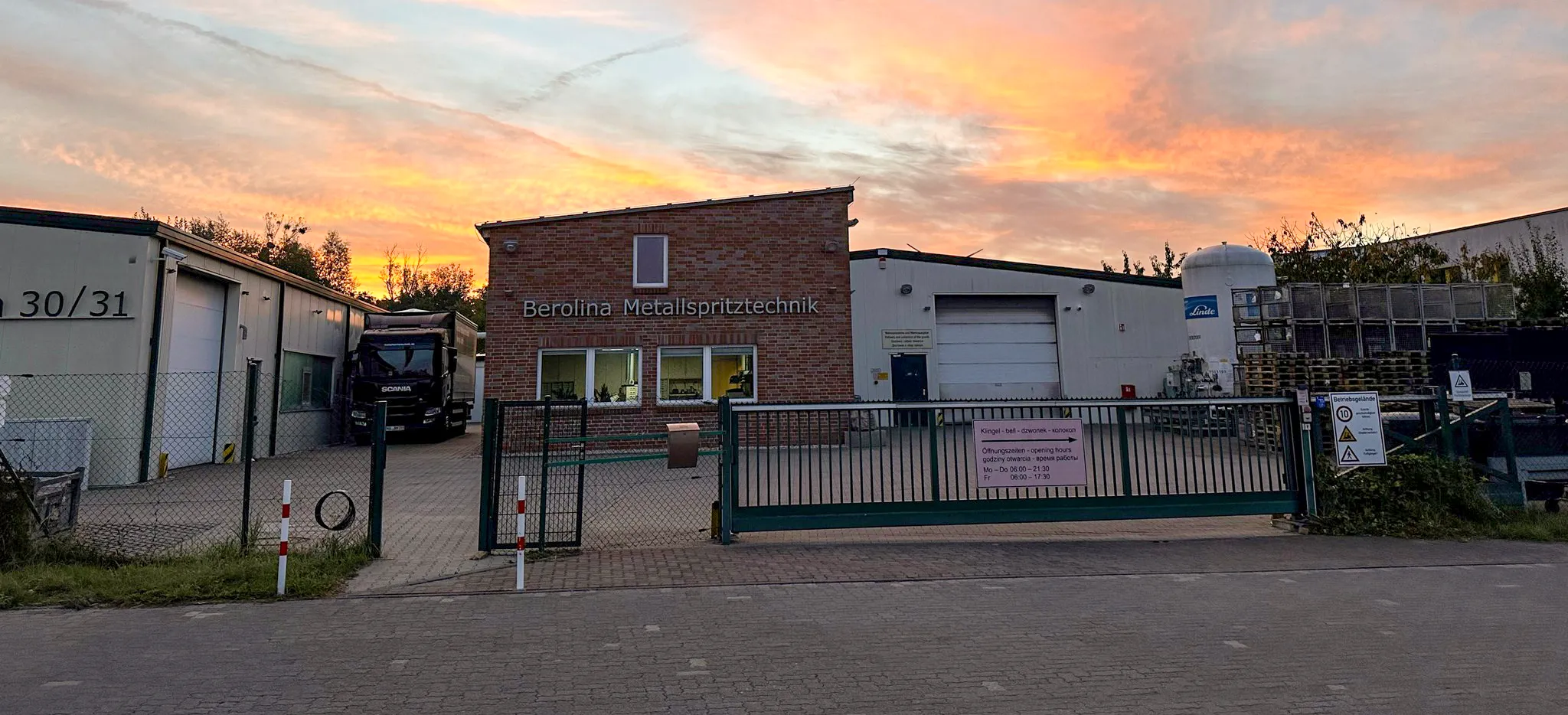 Gebaeude und Gelände von Berolina Metallspritztechnik Wesnigk GmbH Das Eingangstor vor dem Gebäude mit Backstein-Hauswand und dem Schriftzug Berolina Metallspritztechnik . Nebendran sind Fertigungs- und Lagerhallen zu sehen.